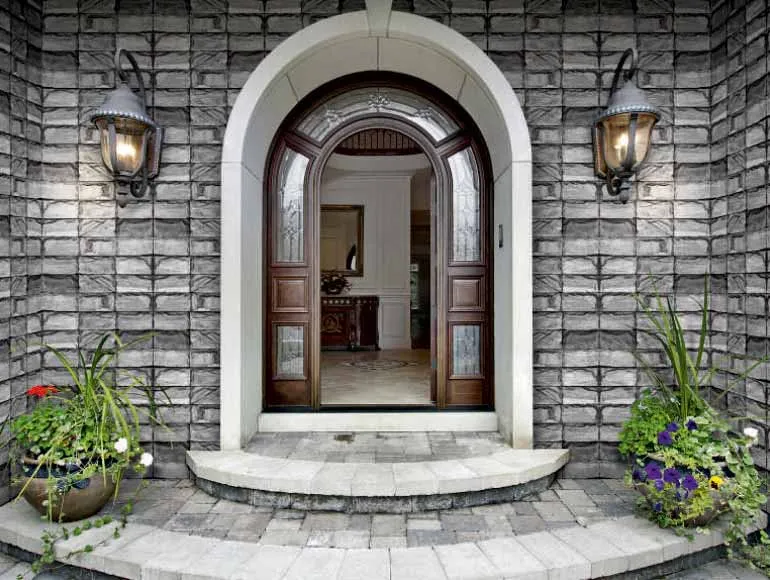 Front elevation design with an arched wooden door featuring glass panels and a gray brick facade